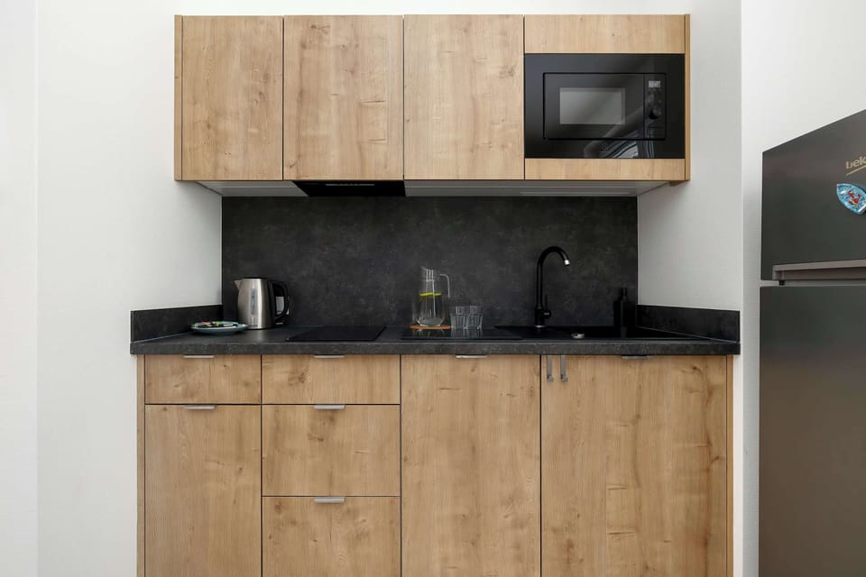 A close-up of the kitchenette reveals dark countertops, a built-in microwave, and high-quality wooden-textured cupboards.