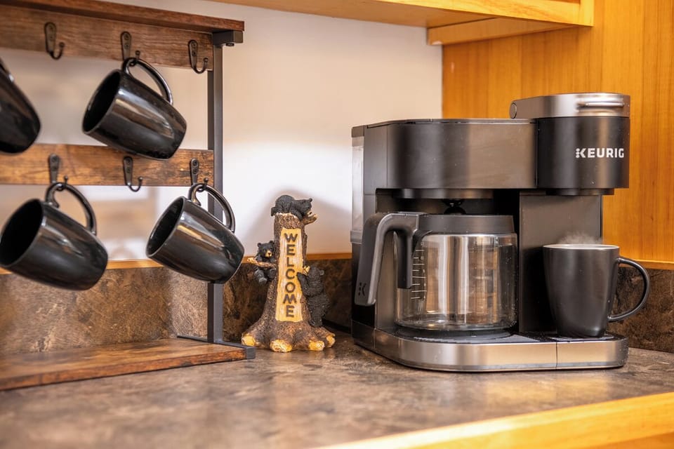 Wake up to your perfect morning brew with this fully-equipped coffee station featuring both drip and Keurig options, plus mugs ready for your first sip.
