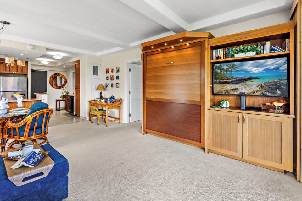 Relax in your spacious living area featuring a clever Murphy bed, entertainment center, and tropical touches that blend comfort with island style.