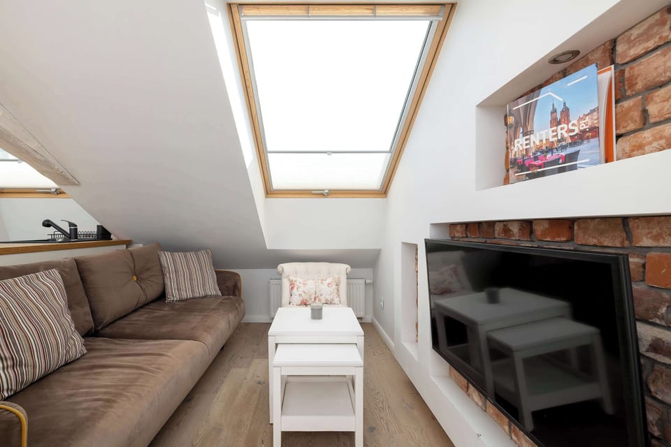 The living area showcases a plush brown sofa facing a modern television set into a stylish dark alcove, creating a perfect spot for relaxation.