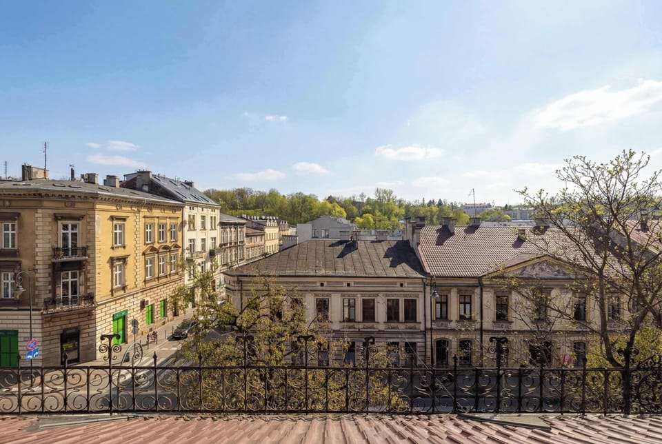 The view from the window overlooks a charming city street lined with historic buildings and lush green trees under a clear blue sky.