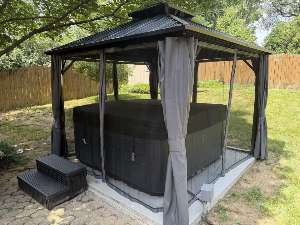 Gazebo with see through curtains showing backyard hot tub