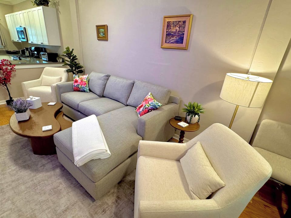 Colorful living room with comfortable Crate & Barrel couch, swivel chairs, and nested coffee table. Easy access to dining area and kitchen. 