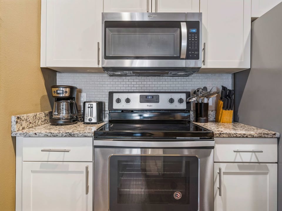 Stainless steel microwave and oven with coffee maker and toaster on granite countertop