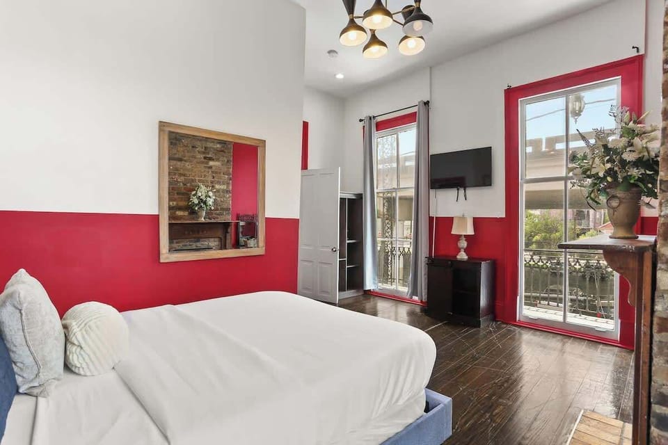 Spacious bedroom with a queen bed, Smart TV, and large windows overlooking the neighborhood. Bright, airy layout with high ceilings and direct access to storage and living areas.