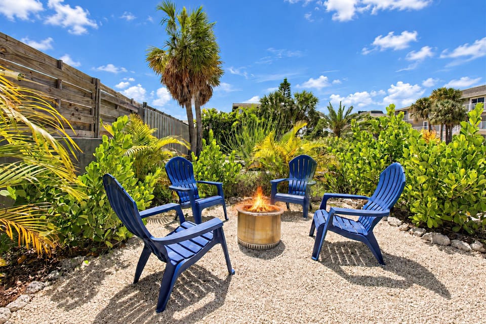 Tropical fire pit lounge with Adirondack chairs and private garden vibes