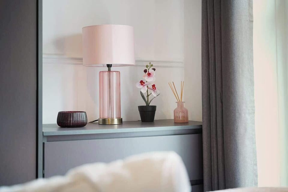 A well-appointed double bedroom perfect for longer stays, offering a peaceful and homely environment. A big window brightens the room naturally, while a wall-mounted mirror enhances usability and style.