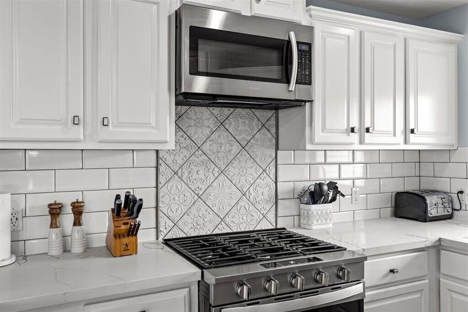 Sleek chef’s kitchen with gas range, quartz counters & tiled flair