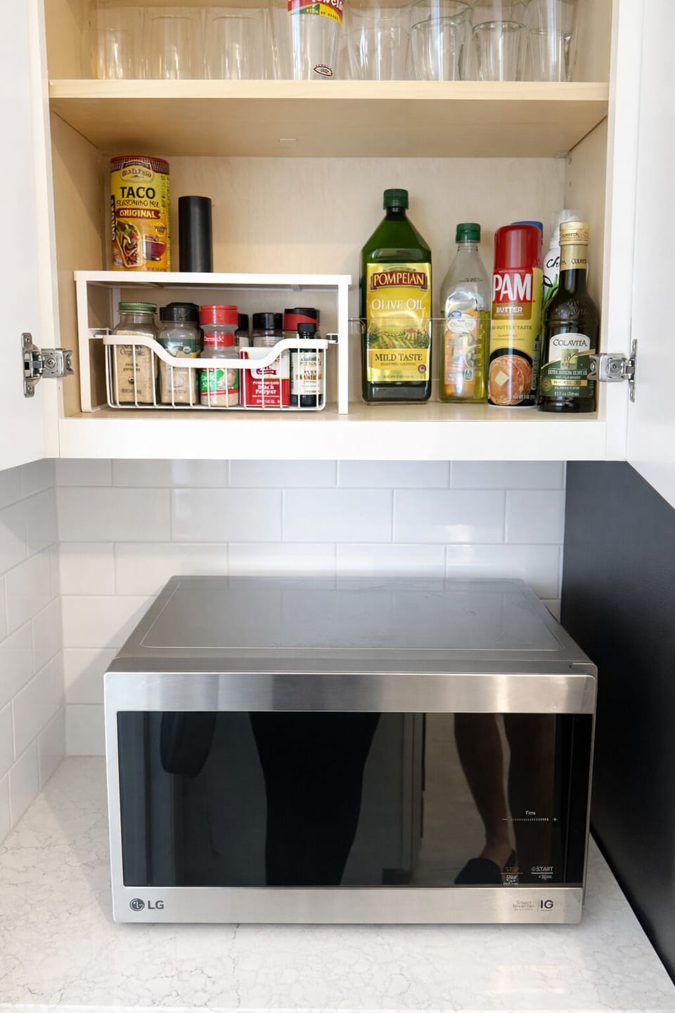Microwave with stocked spice and cooking essentials.