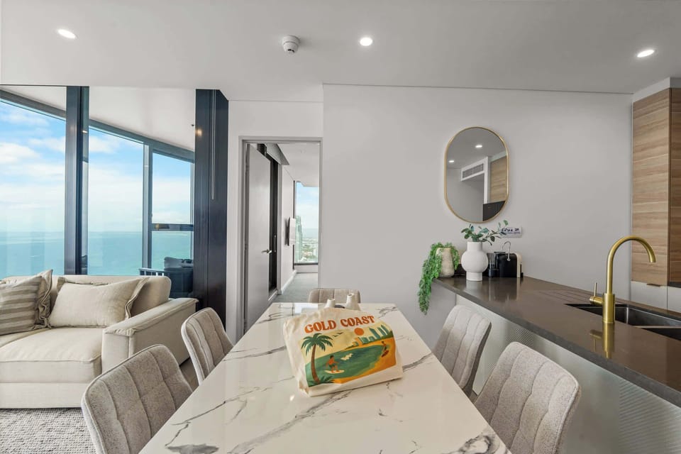 Modern marble dining table for six overlooking the coastline — guests may even spot one of our custom Gold Coast tote bags during their stay.