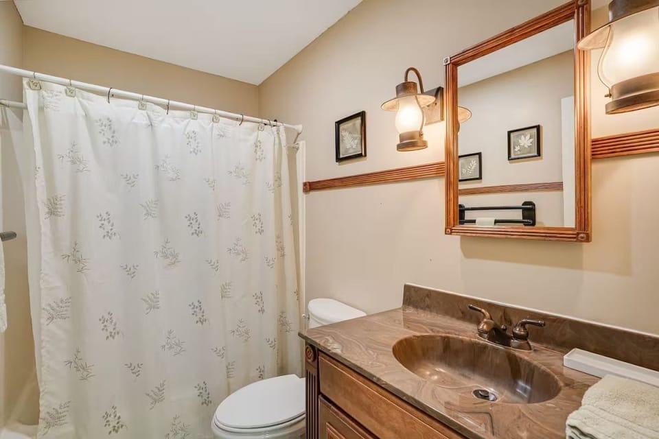 Bathroom featuring a vanity with lantern sconces and a shower curtain.