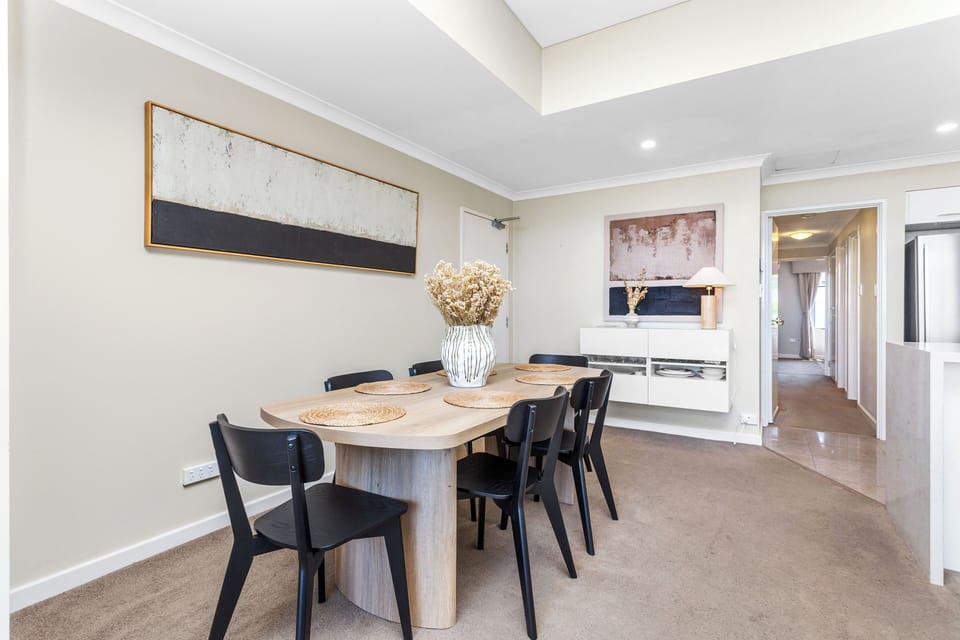 Host intimate dinners in this stylish, contemporary dining space featuring a sleek timber table, designer black seating, and striking abstract wall art.
