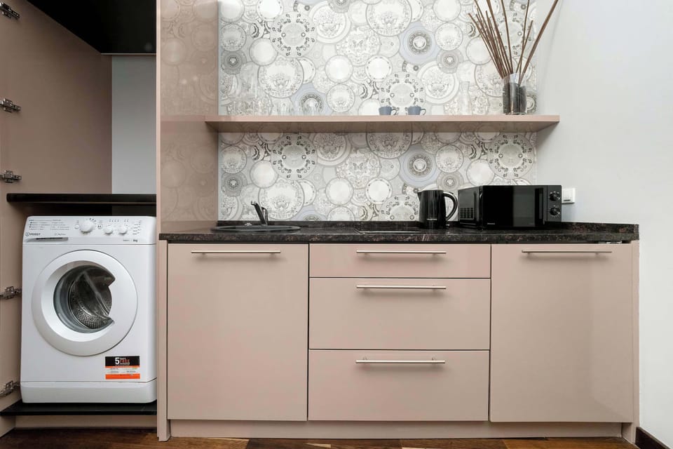 A practical kitchenette area in the studio with cabinets and a washing machine built in. The smart storage solutions keep the open space tidy.