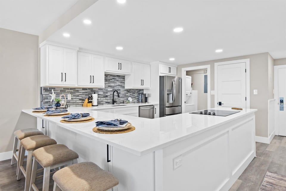 Your modern kitchen features pristine white cabinetry, gleaming quartz countertops, and premium stainless steel appliances for effortless meal preparation.