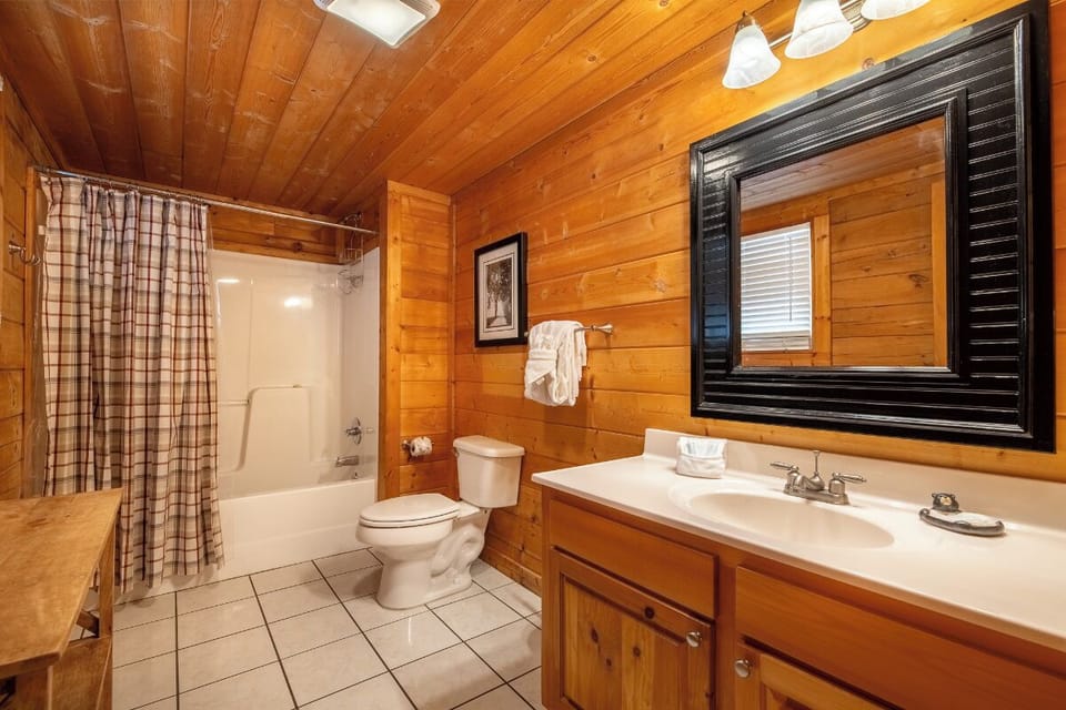 Unwind in your rustic bathroom featuring warm wood paneling and cozy cabin charm.