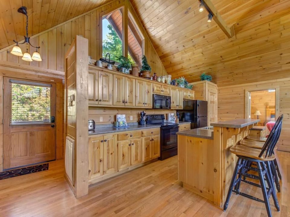 Your rustic cabin kitchen invites culinary adventures with warm wood cabinets, granite counters, and mountain views through the window.