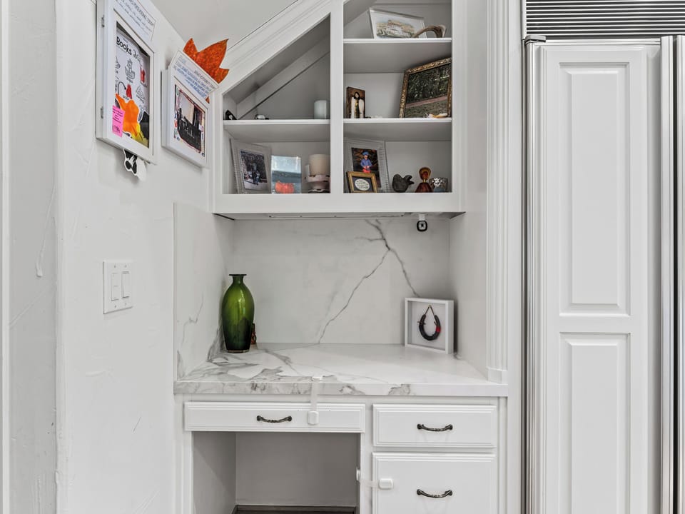 Your perfect workspace awaits with elegant built-in storage, marble countertops, and thoughtfully curated shelving for books and treasures.