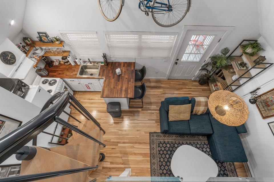 From your loft bedroom, admire the open-concept space below with warm wood floors, modern kitchen, and cozy living area.