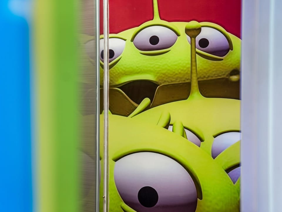 Close-up of a colorful green alien character illustration framed by vibrant panels.