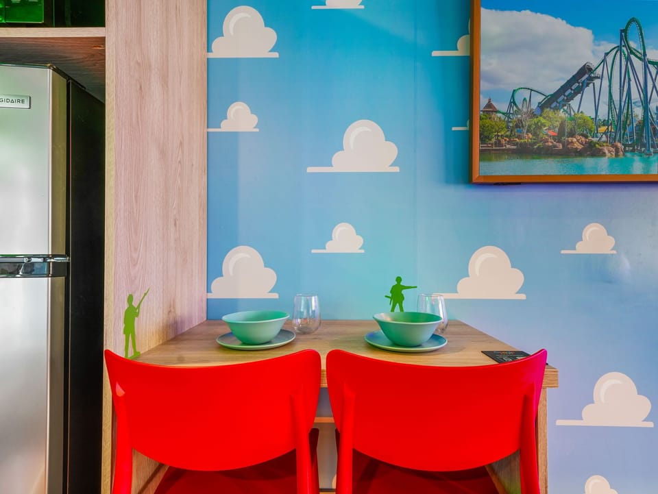 Compact dining area with colorful red chairs and playful cloud-themed wall art.