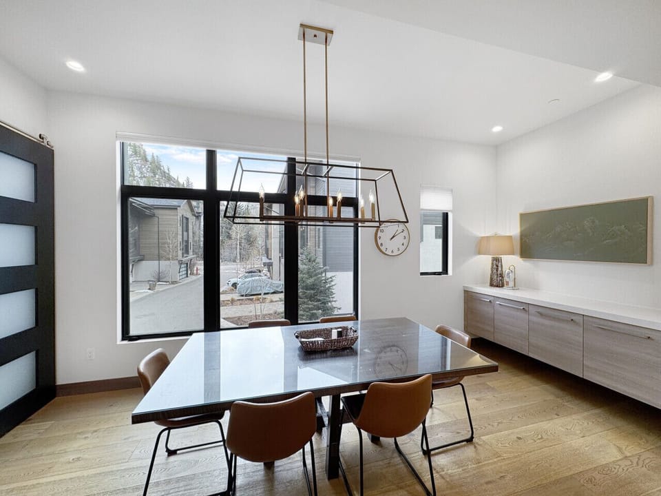 Twelve seats, one long mountain view. The dining table holds eight, the island pulls in four more, and Beaver Creek slopes fill the window behind it all