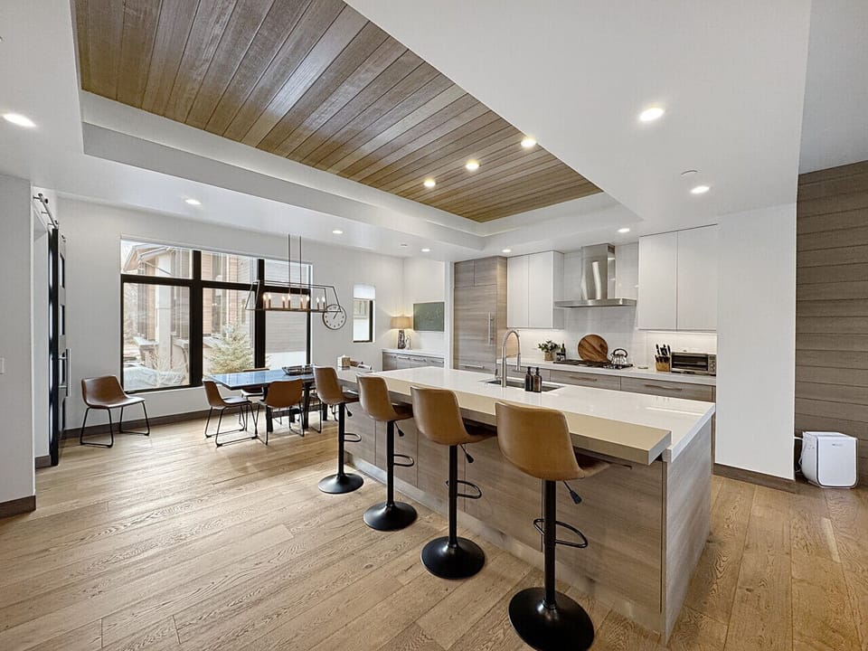 A kitchen that works as beautifully as it looks. Island sink, generous counter, fridge within reach, and sunlit dining just steps beyond. Cook here. Linger there