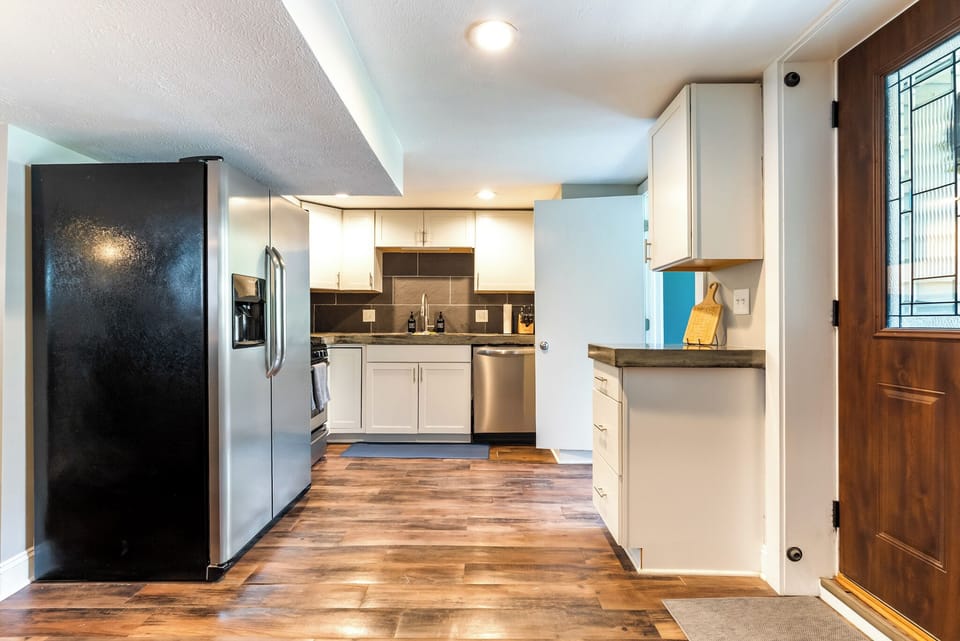 Welcome to the Garden Level Suite! The private entryway opens up directly to a clean, bright layout featuring a fully equipped kitchen with a full-size refrigerator, oven, and ample counter space.