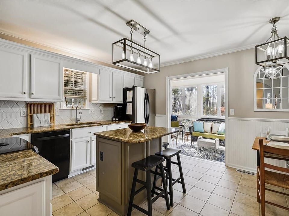 A stylish kitchen combines modern finishes and coastal charm, complete with open sightlines toward the sunny outdoor deck.