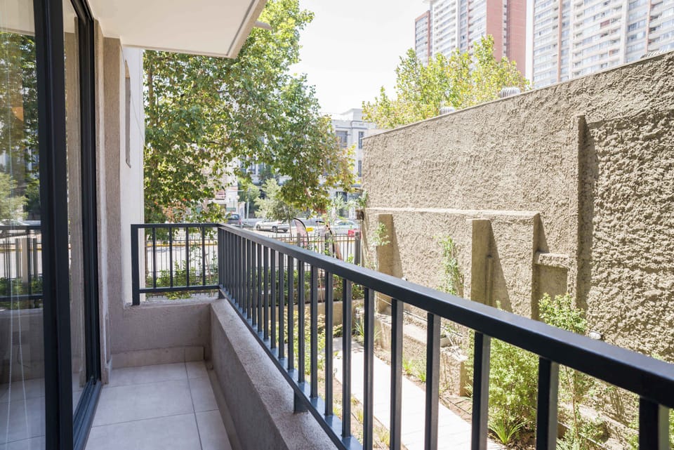 Enjoy your morning coffee on this cozy balcony with city views and lush greenery.