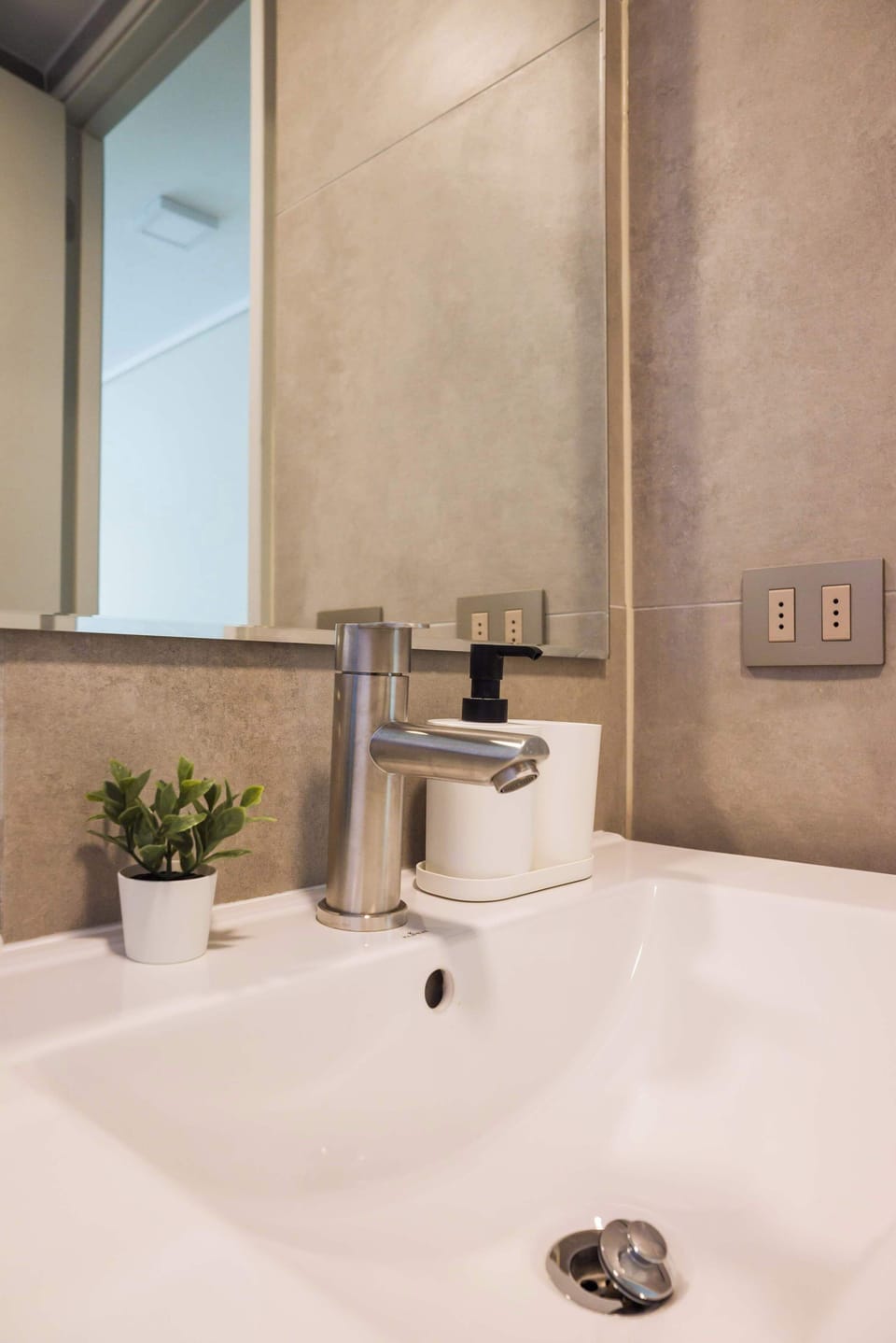 Modern and stylish bathroom with sleek fixtures and a touch of greenery for a refreshing stay.