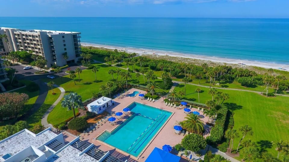 Oceanfront pool area with direct beach access and lush greenery