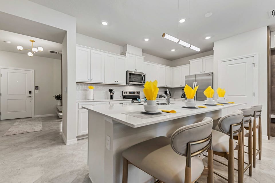 Sleek, all-white kitchen with a quartz island and comfy barstools-perfect for breakfast chats and evening cocktails!