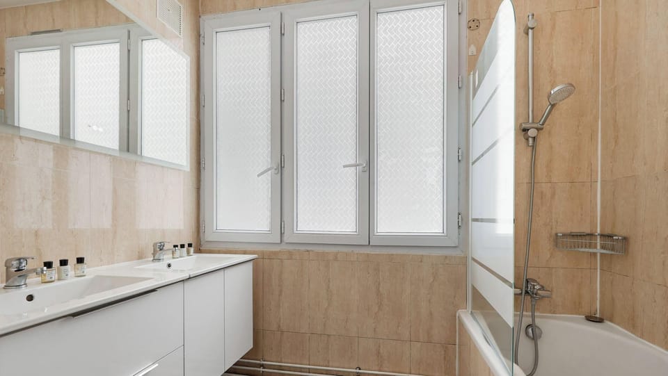 Première salle de bain équipée avec baignoire, deux lavabos