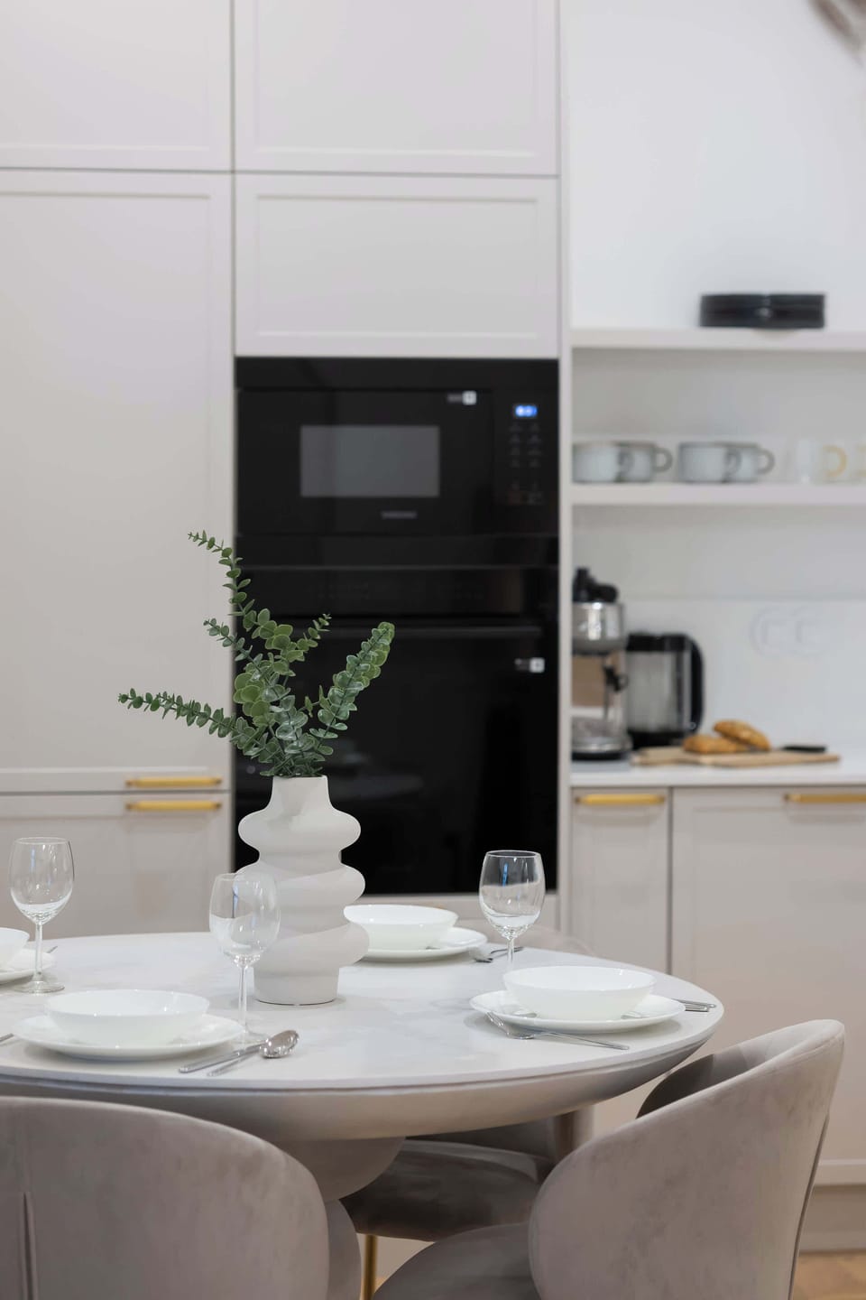 A compact dining nook beside the kitchen with a round table and chairs. The arrangement maximizes space efficiently. The design feels clean and modern.