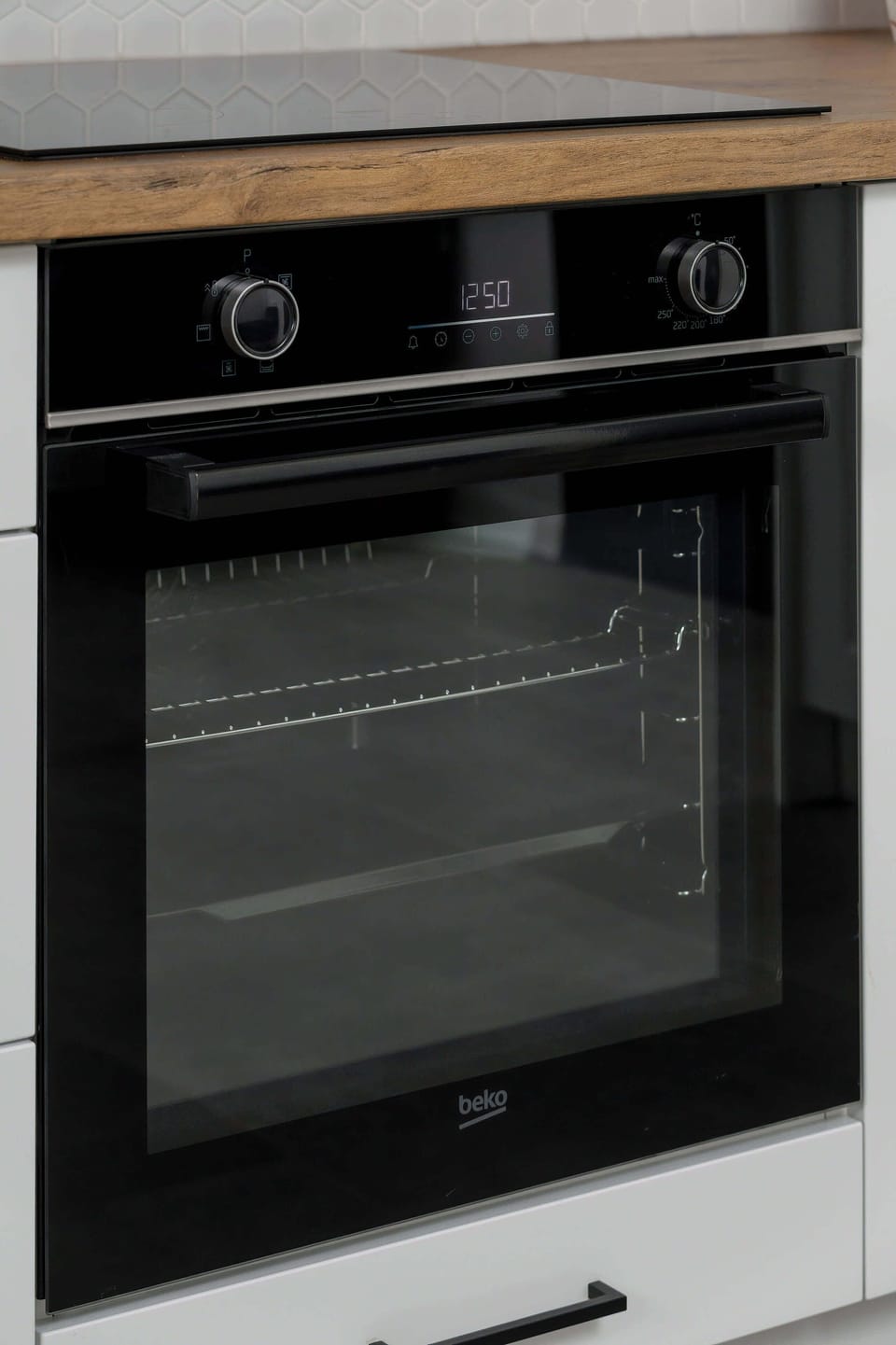 A focused shot of a built-in black oven surrounded by white cabinetry. This high-quality kitchen appliance ensures guests have everything they need for home-cooked meals.