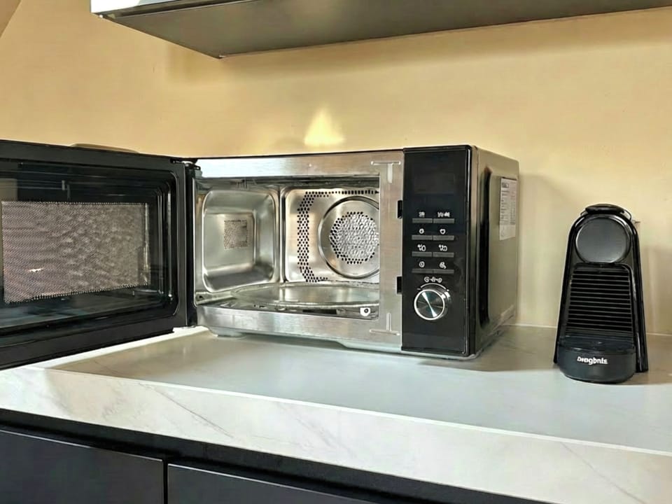 Modern microwave oven with stainless steel interior and control dial, placed on a sleek kitchen countertop for quick and convenient cooking.
