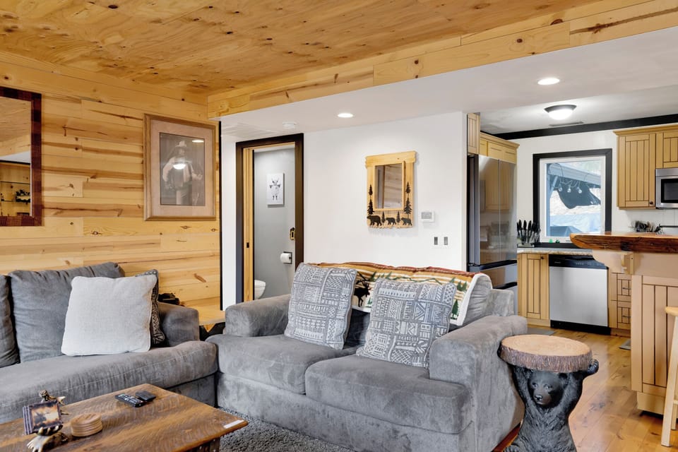 Cozy mountain living room with a stone fireplace, comfy seating, and smart TV—perfect for relaxing evenings, movie nights, and warm cabin vibes after outdoor adventures.