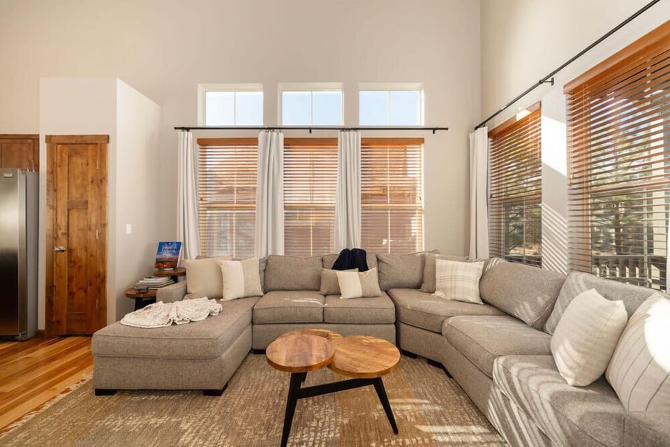 Sink into plush sectional seating surrounded by warm wood tones and natural light streaming through wooden blinds.