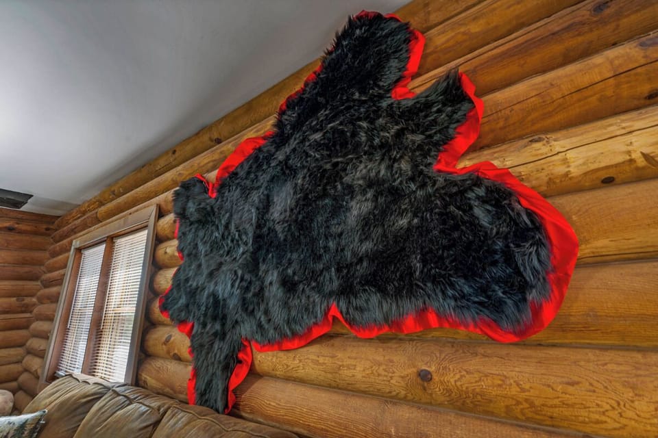 Cozy up in your rustic log cabin retreat where charming details like this playful bear pelt create an authentic mountain atmosphere.