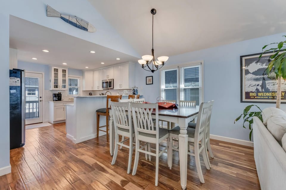 Gather around this welcoming dining table where you'll share meals in the bright, open-concept space with gleaming hardwood floors and coastal charm.
