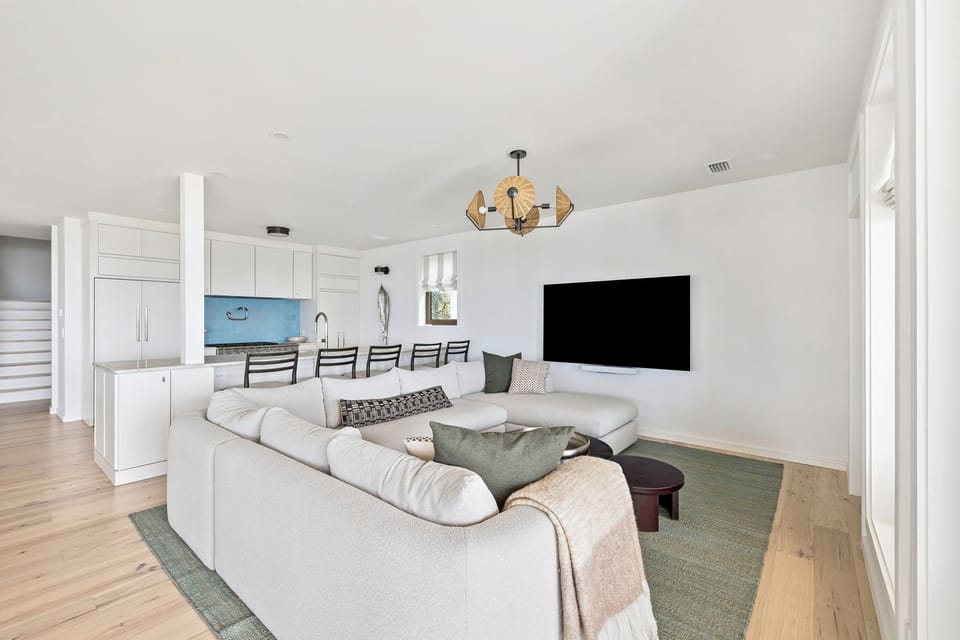 Relax in your open-concept living space with plush seating, modern kitchen, and large TV for cozy evenings.