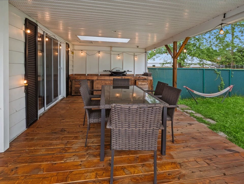 Covered patio with outdoor dining, string lights and a hammock overlooking the backyard.