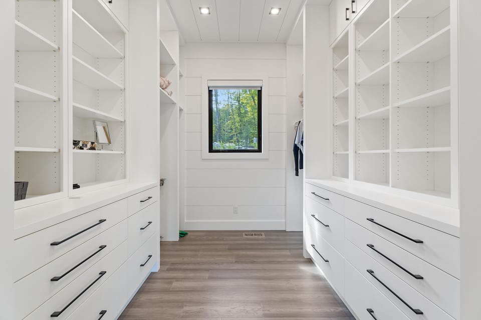 Spacious walk-in closet with sleek white shelving and natural light