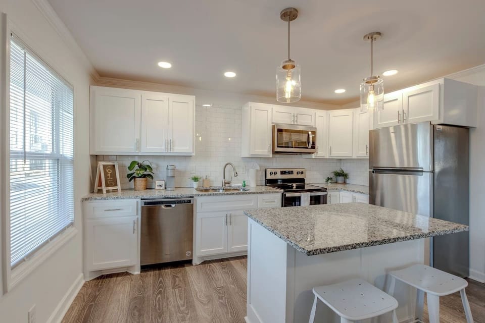 Kitchen with white cabinets, granite island countertop, and stainless steel appliances