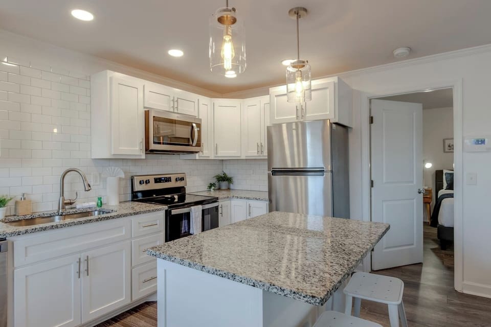 Kitchen with white cabinets, granite island, and stainless steel appliances