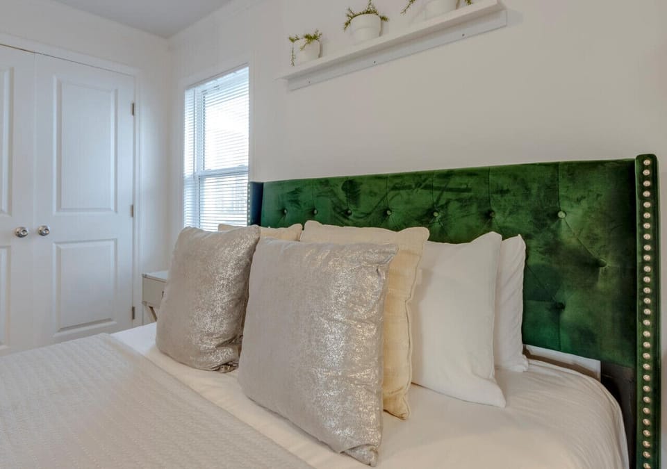 Close-up of the bed with a green velvet headboard and decorative throw pillows