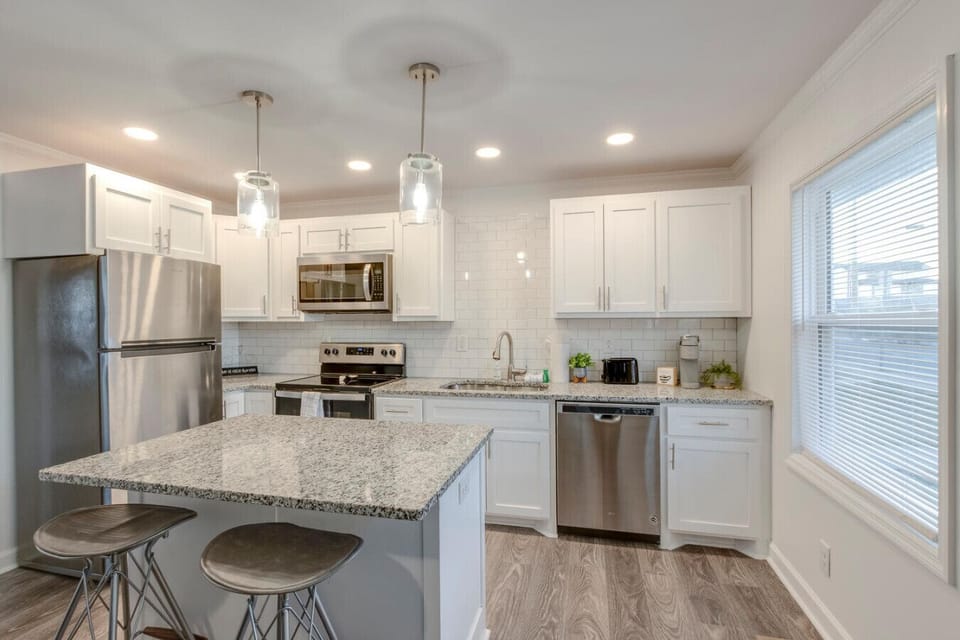 Kitchen with bar stools at the granite island and stainless steel refrigerator