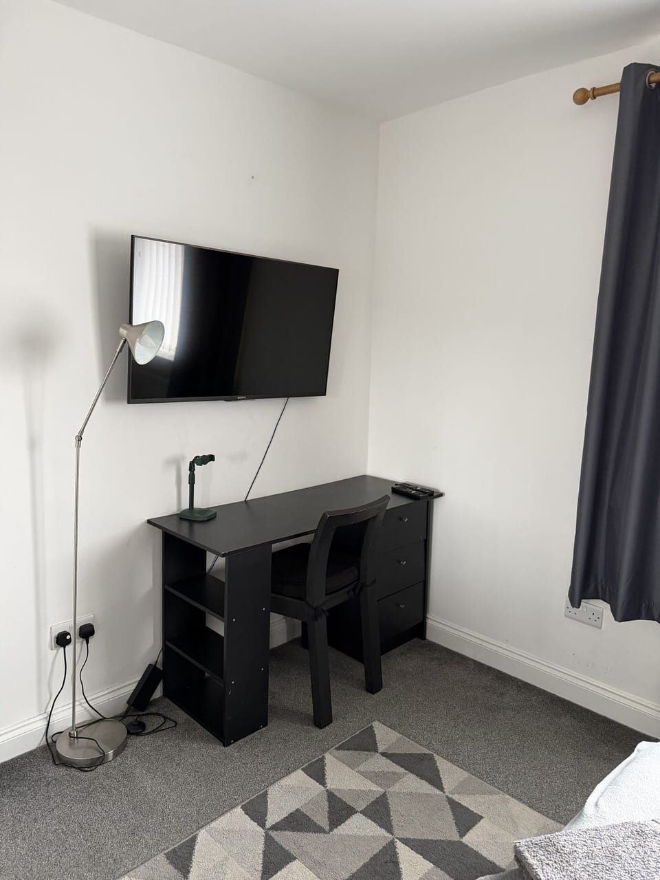 Bedroom with wall-mounted TV and dark wood storage unit