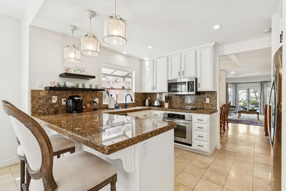 Fully stocked kitchen with granite countertops and bar seating for casual dining.