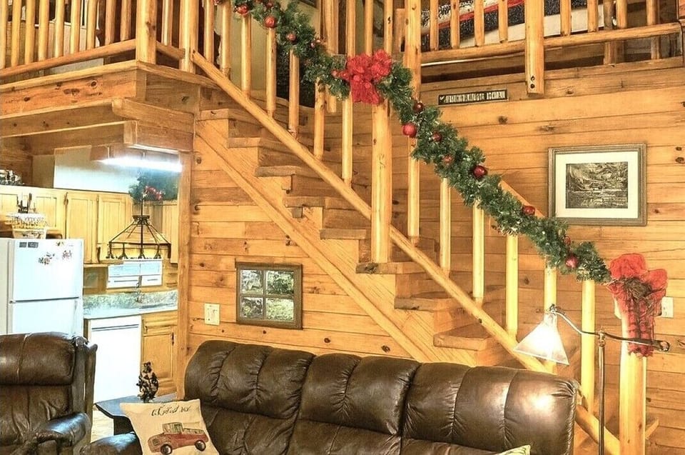 Interior staircase leading to the upper loft level at A Windy Ridge cabin in Wears Valley, Tennessee, decorated with festive holiday garland.